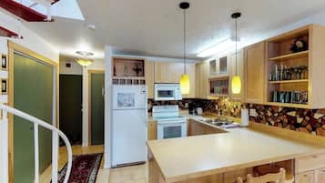 A modern kitchen with wooden cabinets, a central island, and pendant lighting.