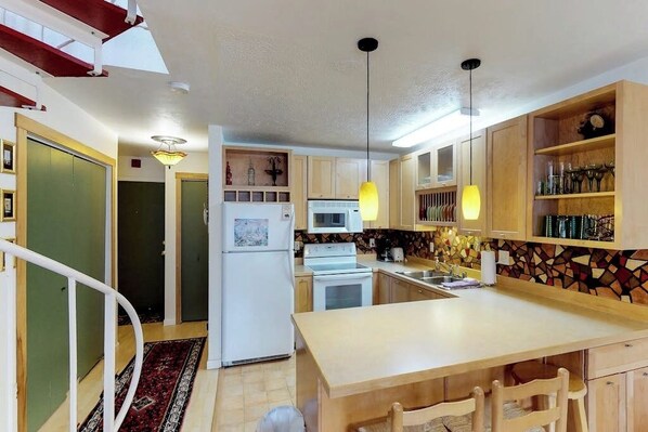 A modern kitchen with wooden cabinets, a central island, and pendant lighting.