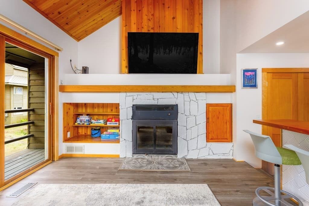 Un interior moderno con chimenea, estanterías de madera y vistas a través de un ventanal.