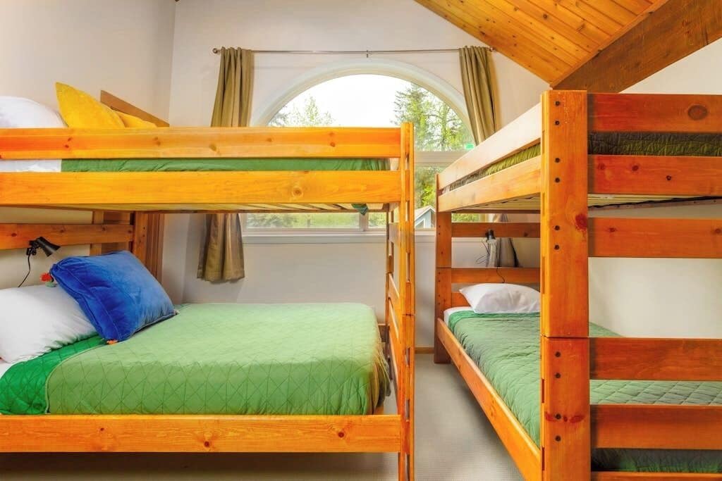 Una habitación con literas, una ventana con cortinas y vistas al exterior.
