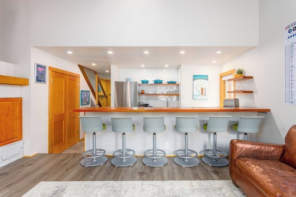 Een moderne keuken met een centraal eiland, barkrukken en een zithoek met een leren bank.