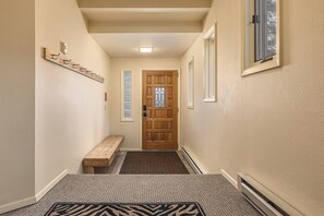 Un couloir avec un banc en bois, une porte dotée d  ’une fenêtre et un porte-manteau fixé au mur.