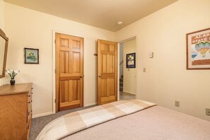 A bedroom with a bed, wooden doors, a dresser, and a framed picture on the wall. - Quiet Girdwood Home w/ Western Exposure Light (Girdwood)