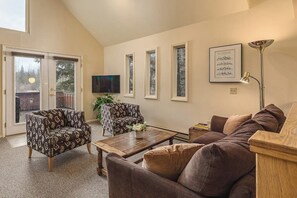 A living room with a sofa, two patterned armchairs, a coffee table, a TV, and a framed picture on the wall. - Quiet Girdwood Home w/ Western Exposure Light (Girdwood)