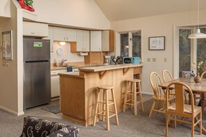 A modern kitchen with a central island, wooden chairs, and a dining table. - Quiet Girdwood Home w/ Western Exposure Light (Girdwood)
