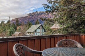 Eine Terrasse mit Tisch und Stühlen mit Blick auf ein Haus und einen Berg.