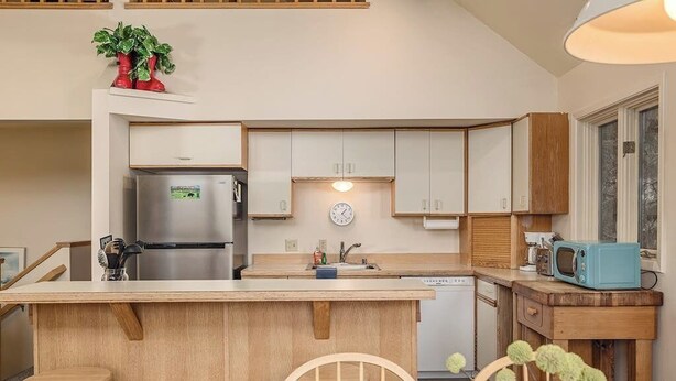 Eine moderne Küche mit einer zentralen Kochinsel, Holzschränken, einem Edelstahlkühlschrank und einer Mikrowelle.