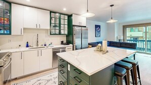 Una cocina moderna con una isla central, electrodomésticos integrados y una zona de estar con vistas.