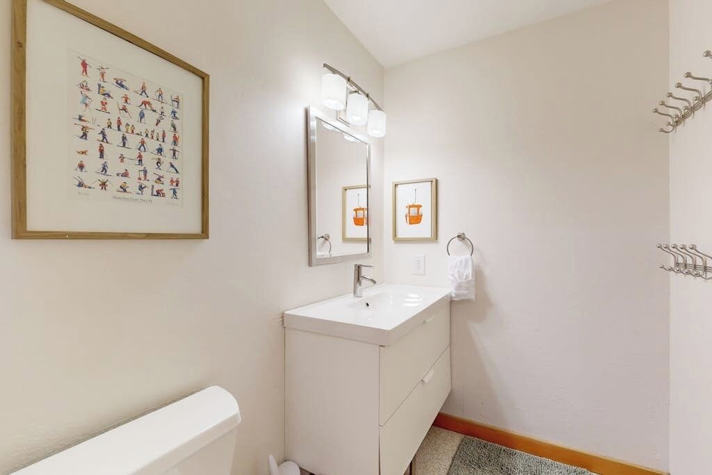 A bathroom with a white sink, a mirror, and a framed picture on the wall.