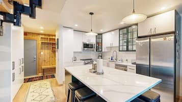 A modern kitchen with a central island, stainless steel appliances, and a wooden accent wall.