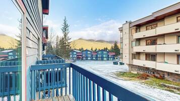 A multi-story building with a balcony, a view of a mountainous landscape, and a parking area.