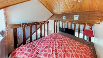 A bedroom with a bed, a television, and string lights.