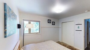 Un dormitorio con cama, ventana, puerta y una lámpara fijada a la pared.