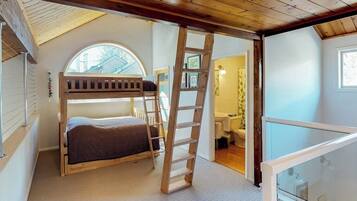 A room with a bunk bed, a wooden ladder, a skylight, and a view of the outside.