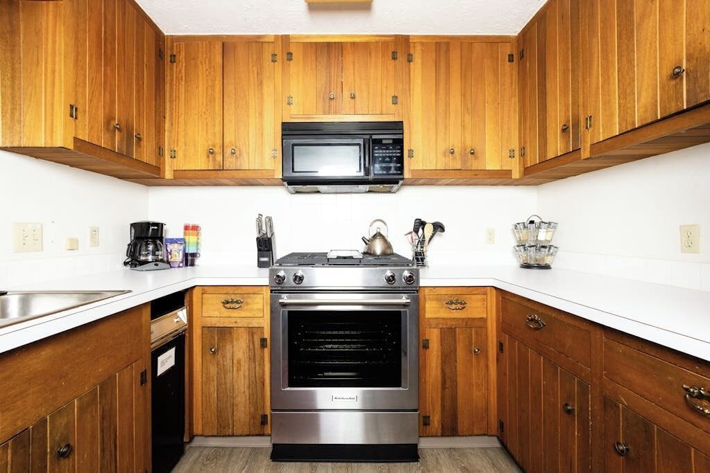 A kitchen with wooden cabinets, a stainless steel stove, a microwave, and a dishwasher.