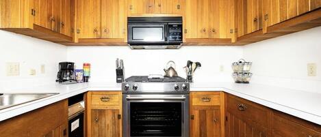 A kitchen with wooden cabinets, a stainless steel stove, a microwave, and a dishwasher.