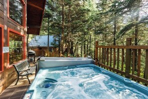 Un jacuzzi en una terraza de madera rodeado por un bosque.