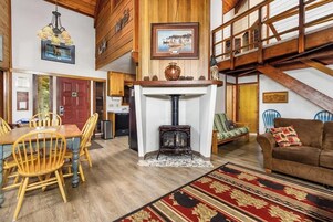 Amplia sala de estar con chimenea, muebles de madera y un techo alto.