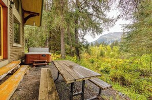 Ein Holztisch mit Bänken, ein Whirlpool und ein Haus mit einer Veranda.