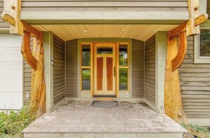 Eine Holztür mit Fensterglas, eine Betonveranda und eine Metalldoormat.