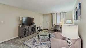 A living room with a television, sofa, coffee table, and lamp. - Practical Anchorage Apartment Built for Families (Anchorage)