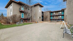 A residential building with a courtyard, balconies, and a paved area with benches. - Practical Anchorage Apartment Built for Families (Anchorage)