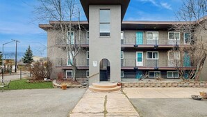 A multi-story residential building with a central entrance, balconies, and a clear sky. - Practical Anchorage Apartment Built for Families (Anchorage)