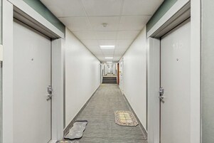 Un pasillo con puertas numeradas 115 que conducen a una escalera.