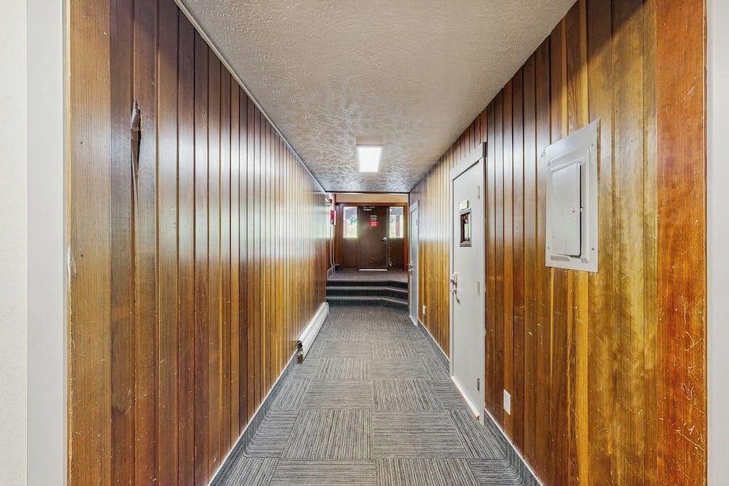 Un pasillo con paneles de madera en las paredes y suelo alfombrado.