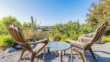 An outdoor seating area with two chairs and a table, surrounded by gravel and greenery.