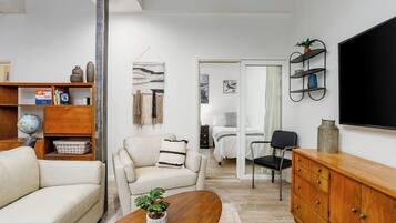 A modern living room with a sofa, armchair, coffee table, and a TV mounted on the wall.