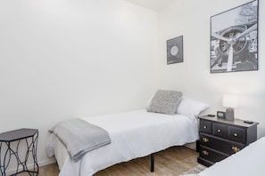 A bedroom with a bed, bedside table, and a wall-mounted picture.