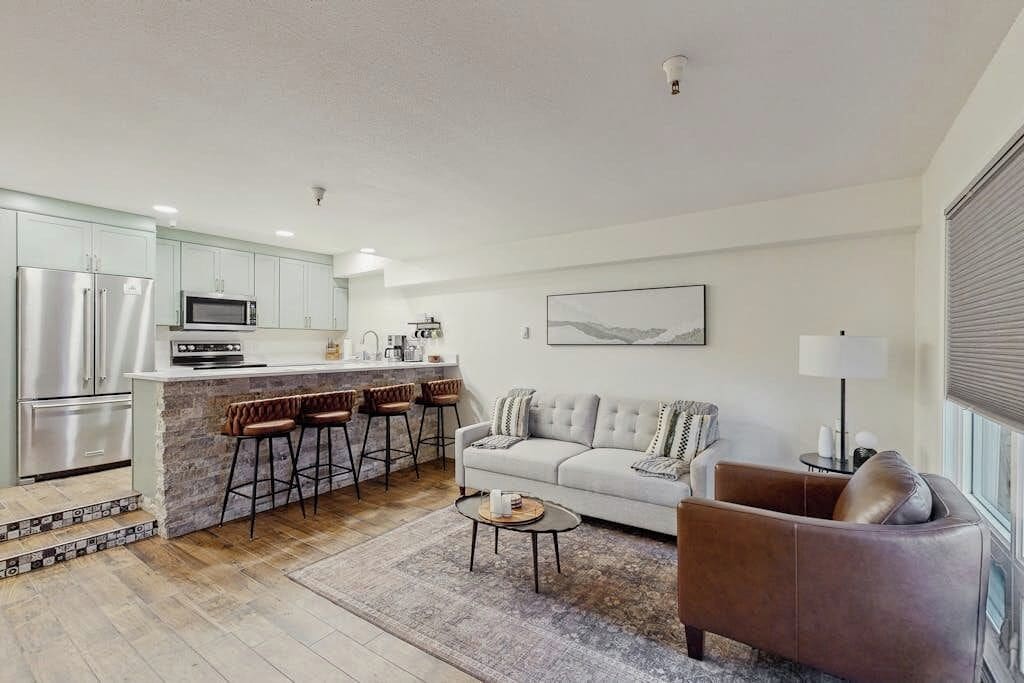 A modern kitchen with a bar area, a sofa, and a coffee table in a living room.