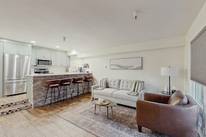 A modern kitchen with a bar area, a sofa, and a coffee table in a living room.