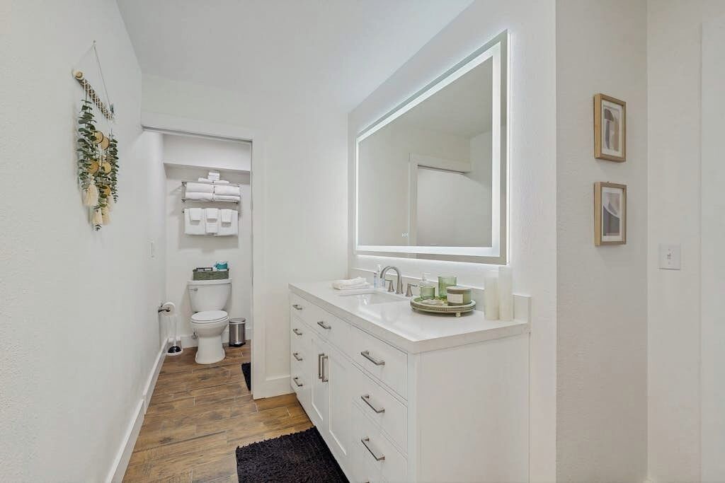 A bathroom with a white vanity, a large mirror, and a toilet.