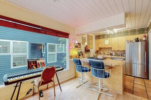 A modern kitchen with a built-in island, bar stools, and a refrigerator. - One-bedroom Loft in Anchorage's Bootlegger Cove (Anchorage)