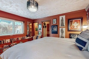A bedroom with a large bed, a bookshelf, and various artworks on the walls. - One-bedroom Loft in Anchorage's Bootlegger Cove (Anchorage)