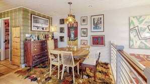 Et spiseområde med et træbord og stole, en lysekrone og kunst på væggene.