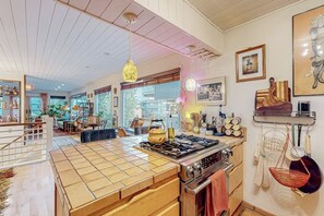 A kitchen with a tiled island, stainless steel appliances, and hanging kitchen utensils. - One-bedroom Loft in Anchorage's Bootlegger Cove (Anchorage)