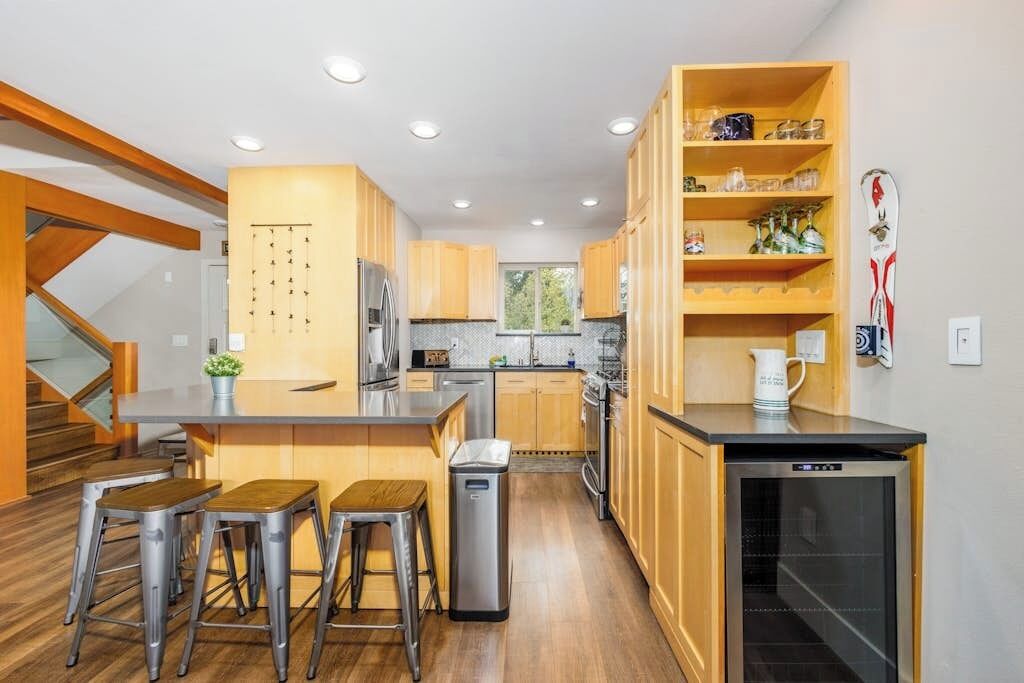 Una cocina moderna con gabinetes de madera, un refrigerador de acero inoxidable y un lavavajillas empotrado.