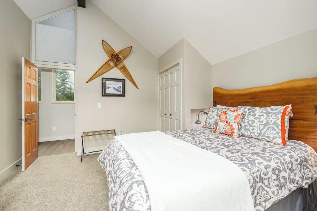 A bedroom with a sloped ceiling, a bed with patterned bedding, a wooden headboard, and a wall-mounted decorative item.