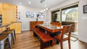 Una cocina moderna con armarios de madera, una mesa de comedor con bancos y obras de arte en las paredes.
