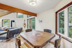 A dining area with a large wooden table, chairs, and a guitar on the wall. - Mountain Chalet w/ Sauna + Patio 0.5mi to Alyeska (Girdwood)