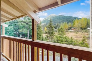 A wooden balcony with a view of a mountainous landscape and dense forest. - Mountain Chalet w/ Sauna + Patio 0.5mi to Alyeska (Girdwood)