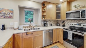Una cocina moderna con armarios de madera, electrodomésticos de acero inoxidable y una ventana con vistas a zonas verdes.