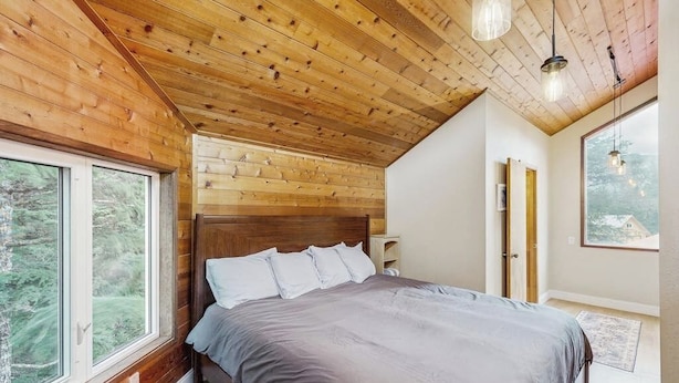 Un dormitorio con techo de madera, una cama grande, una ventana y una puerta.