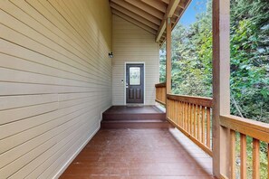 A wooden porch with a dark brown floor and a white railing. - Mountain Chalet w/ Sauna + Patio 0.5mi to Alyeska (Girdwood)