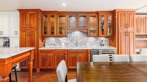 Una cocina con armarios de madera, encimera de mármol y una mesa de comedor con sillas.