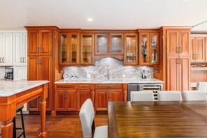 Uma cozinha com armários de madeira, bancada de mármore e uma mesa de jantar com cadeiras.