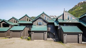 Filas de casas con techos verdes y paredes grises, con montañas al fondo.